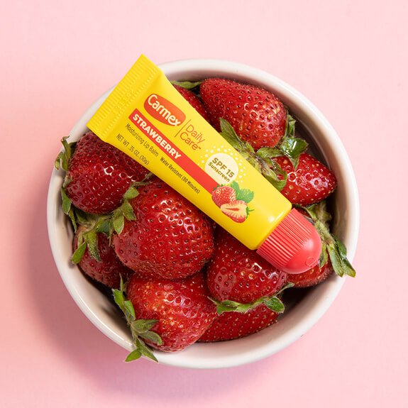 Carmex Daily Care Strawberry Tube Lip Balm in a bowl of strawberries